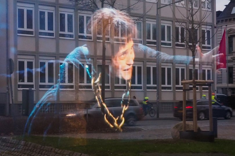 Doppelbelichtung. Eine Frau mit Goldkette vor einem Gebäude. Foto: Stefan Dilz