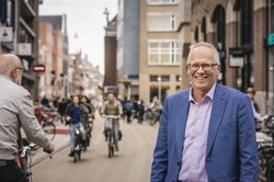 Stadtrat Philip Broeksma im Vordergrund einer Straße mit vielen Fahrradfahrenden in Groningen. Foto: Jeroen van Kooten