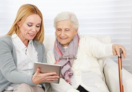 Eine Frau zeigt einer älteren Dame etwas auf einem Tablet. Foto: Robert Kneschke/Fotolia