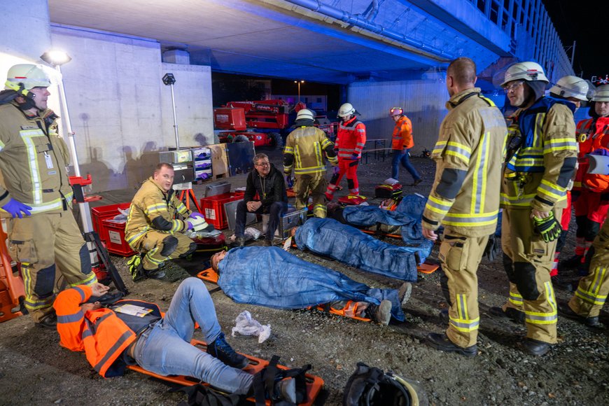 Die Verletzten Personen liegen auf Tragen unterhalb der Eisenbahnbrücke. Foto: Sascha Stüber